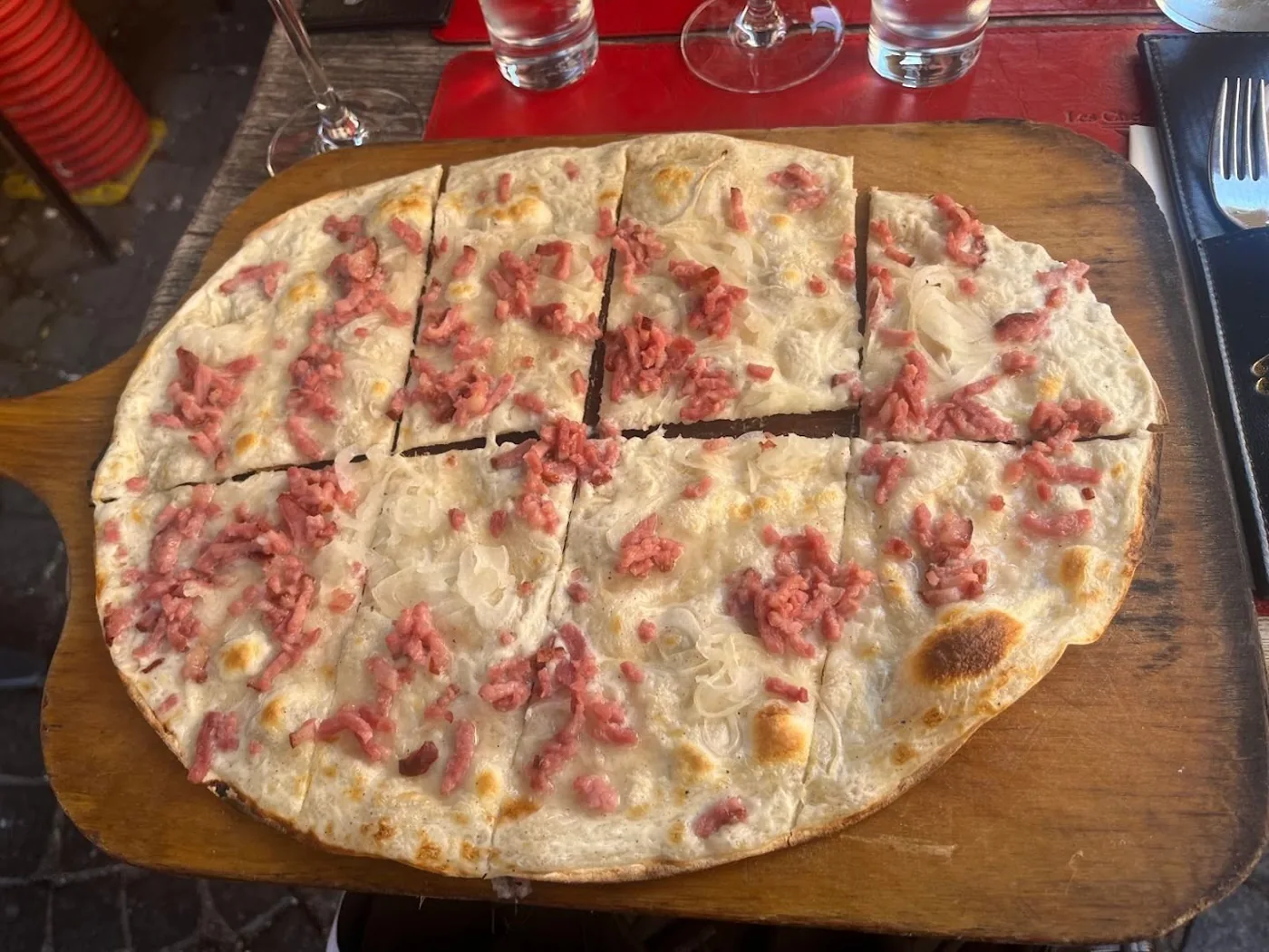 Une tarte flambée traditionnelle servie sur sa planche